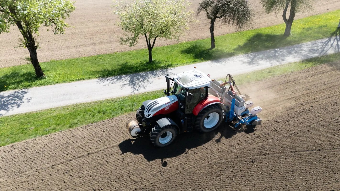 Traktor mit Sämaschine am Feldrand, Luftaufnahme