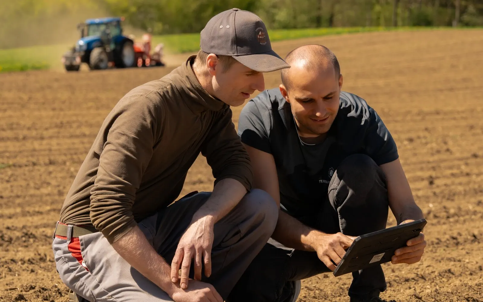 Bodenansprache am Feld mit Tablet, im Hintergrund die Feldarbeit