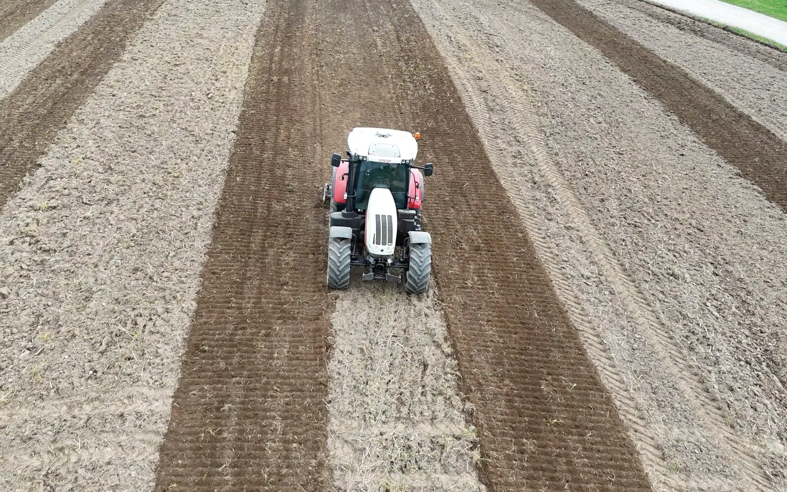 Traktor von vorne zwischen kerzengeraden Spurstreifen