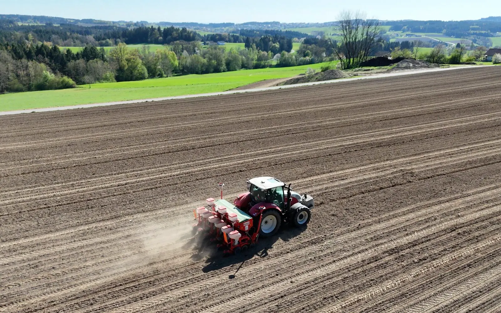 Traktor mit Sämaschine von der Seite bei der Arbeit, mit Staubfahne